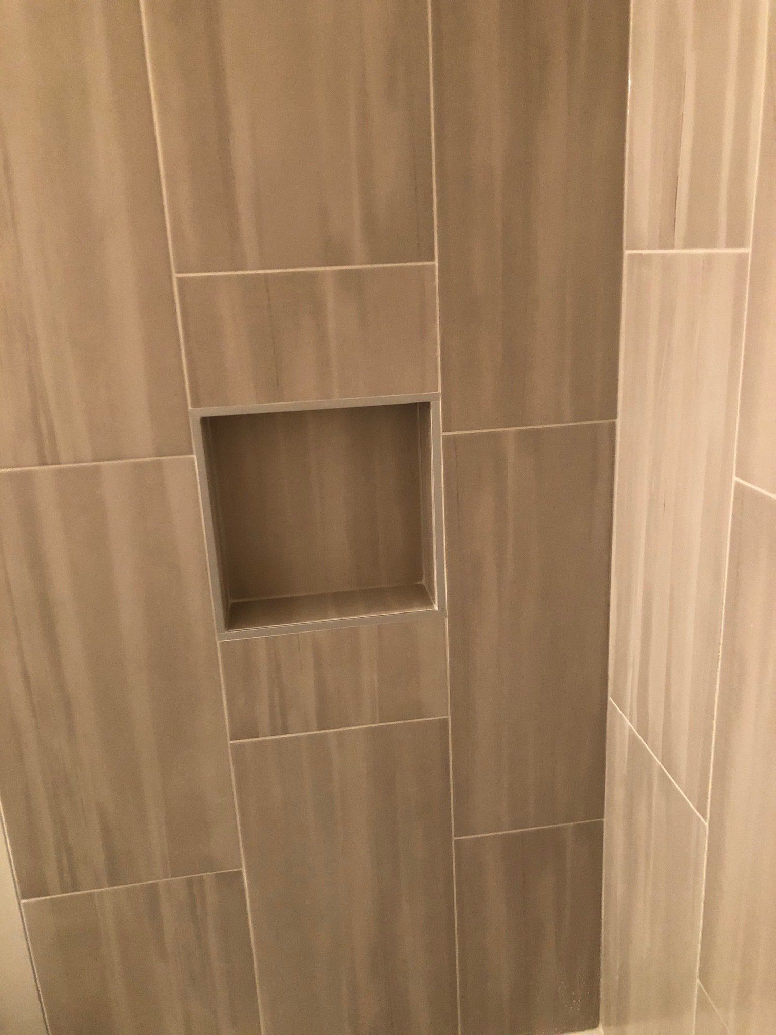 A shower stall with a niche in the wall.