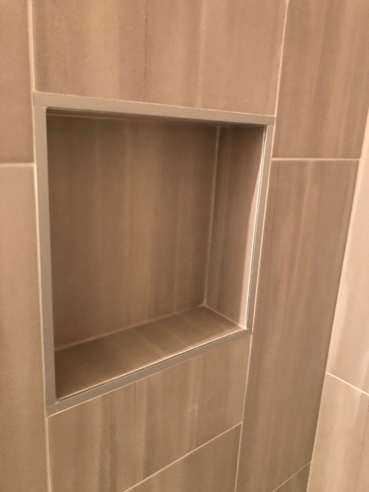 A shower niche in a tiled wall in a bathroom.
