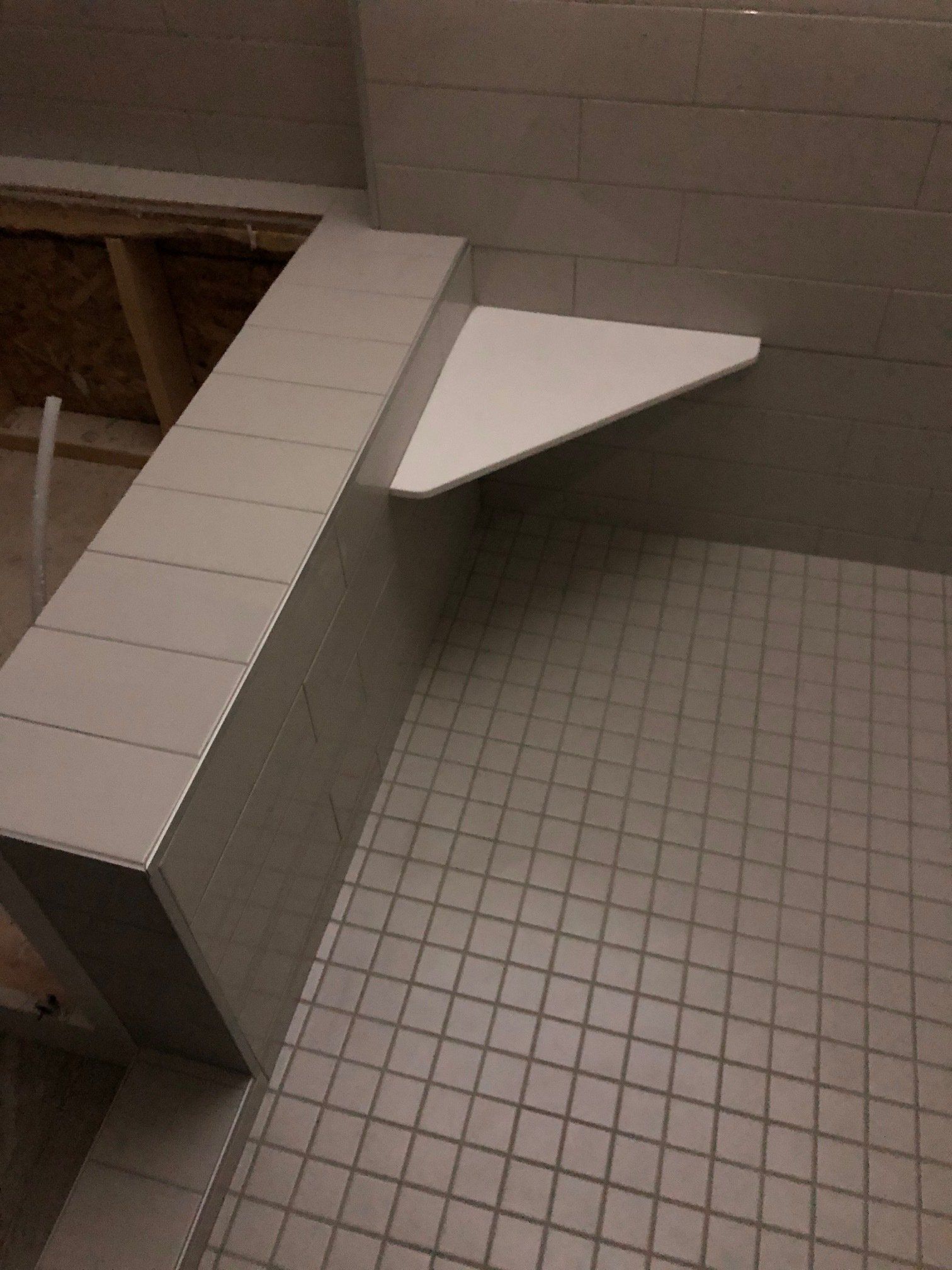 A bathroom with a corner shelf and a tiled floor.