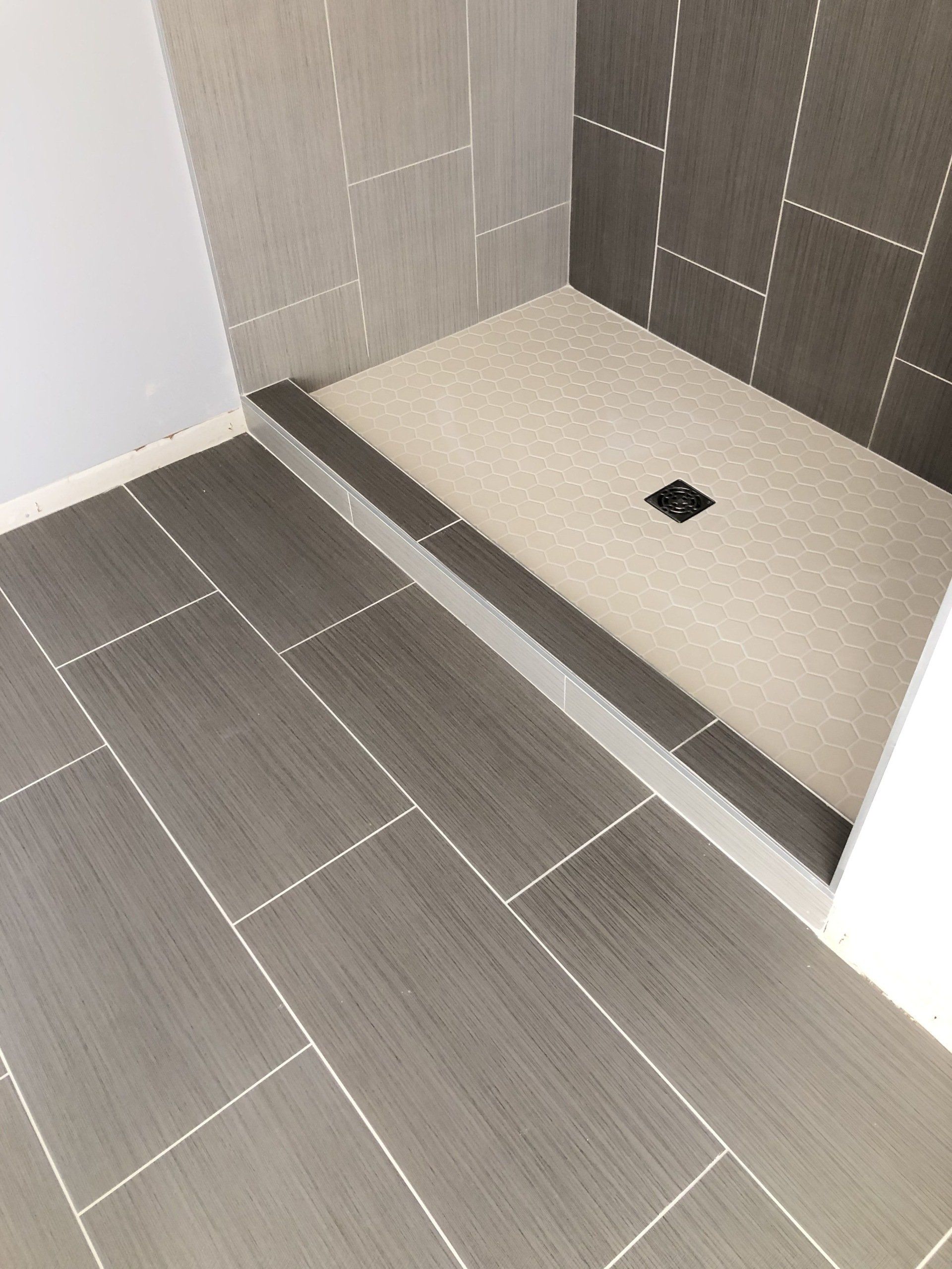 Tub converter to shower | A bathroom with a walk in shower and a tiled floor.