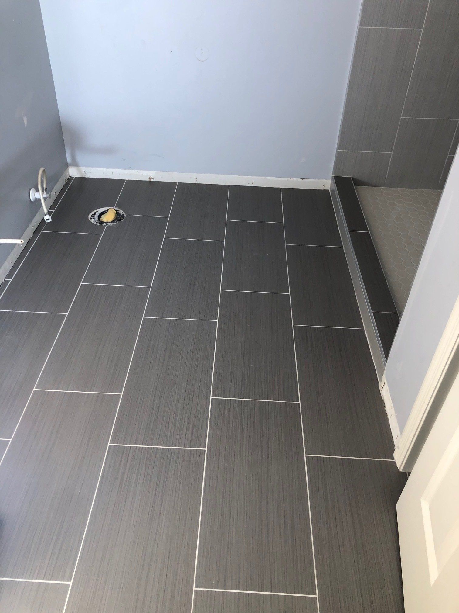 A bathroom with a tiled floor and a toilet drain