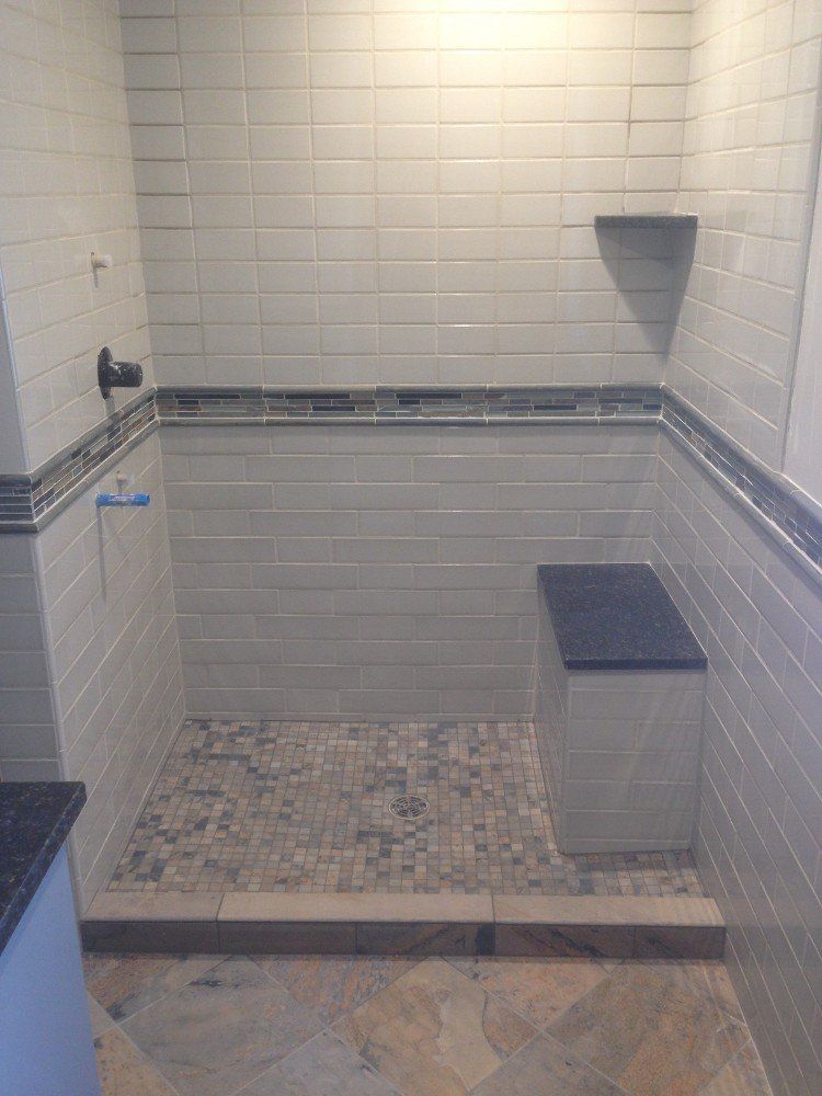 A bathroom for seniors with a walk in shower and a bench.