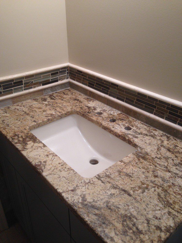 A bathroom sink is sitting on top of a granite counter top.