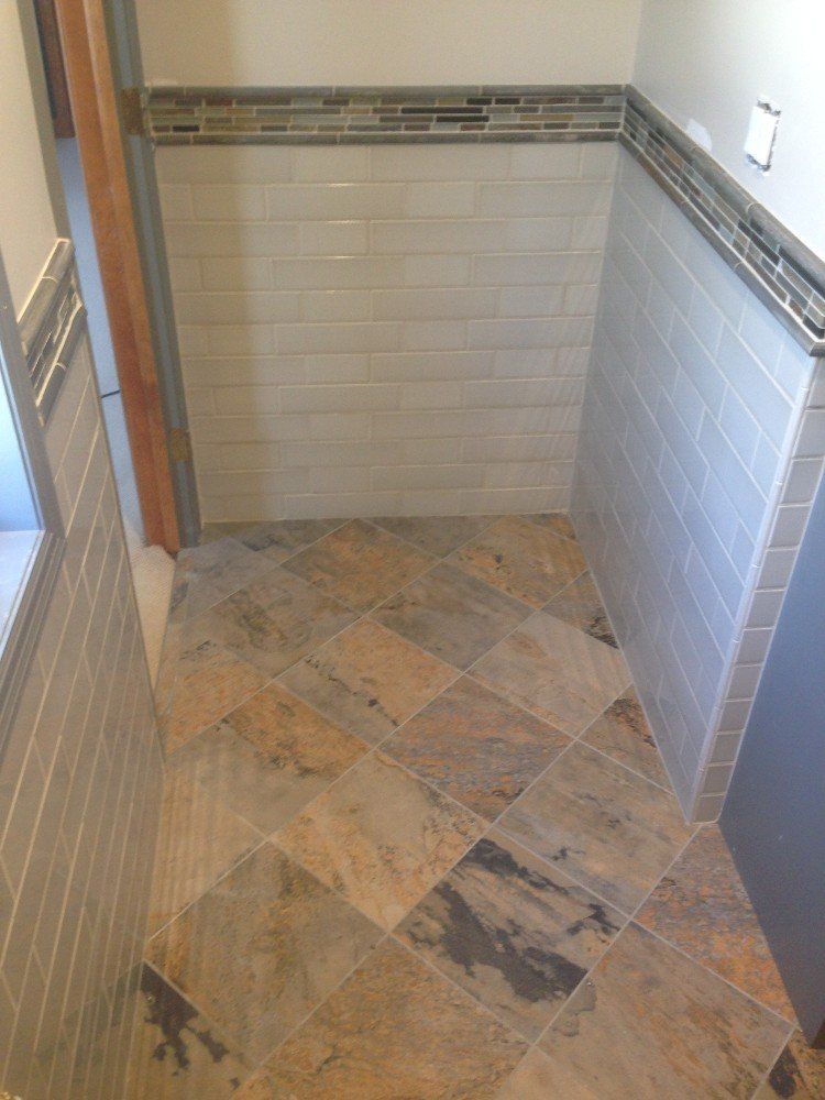 A bathroom with a tiled floor and white tiles on the wall.