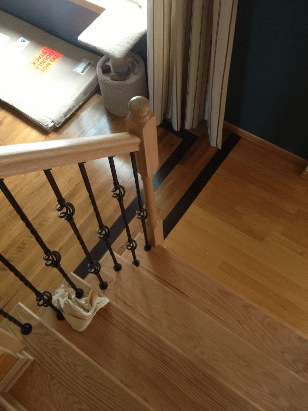 An aerial view of a wooden staircase with a black railing