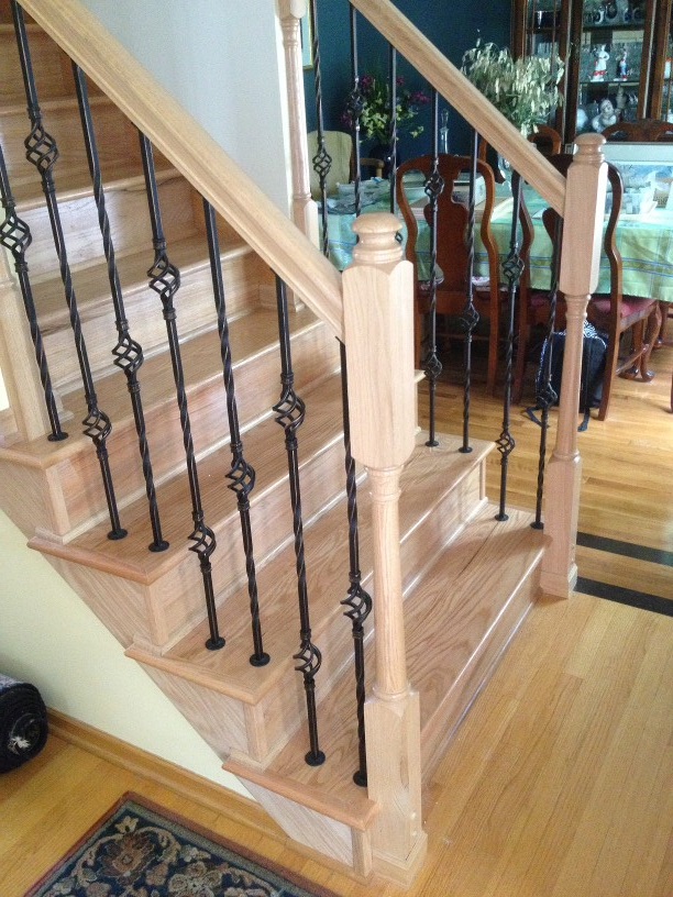 A wooden staircase with a black railing in a living room