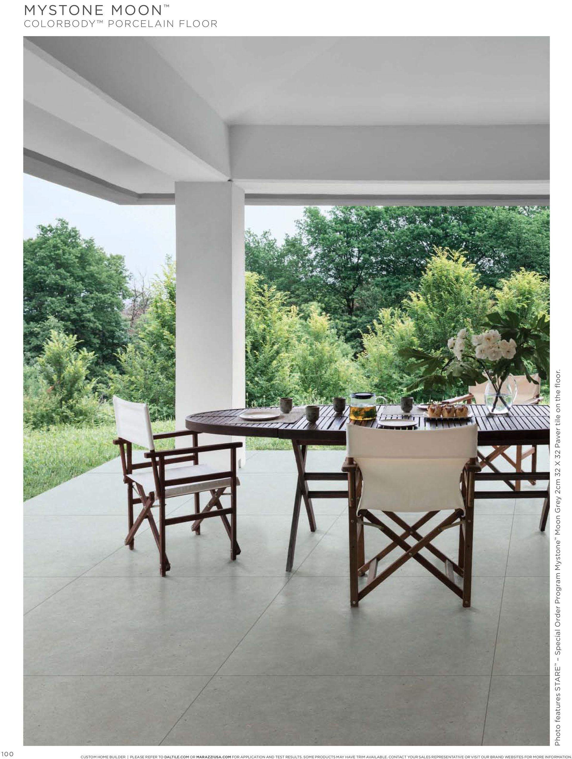 A table and chairs on a patio with trees in the background.