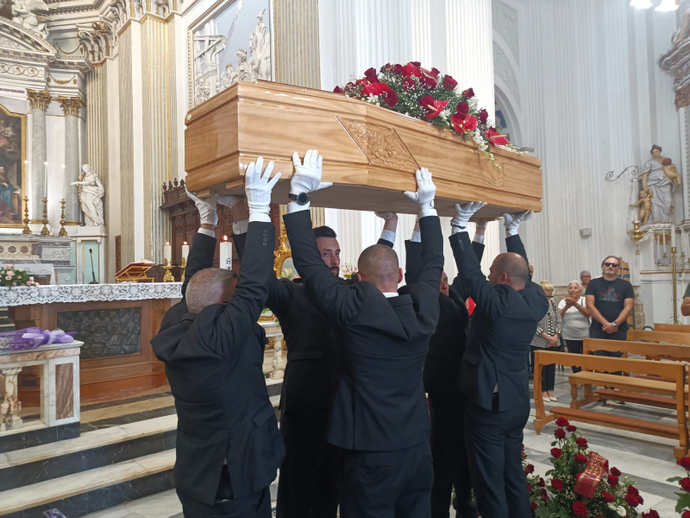 Un gruppo di uomini trasporta una bara in una chiesa.