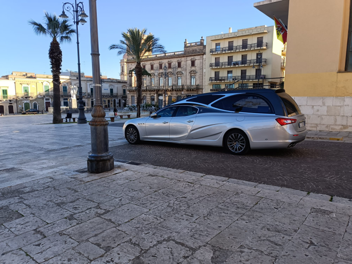 Un'auto argentata è parcheggiata sul ciglio della strada di fronte a un edificio.