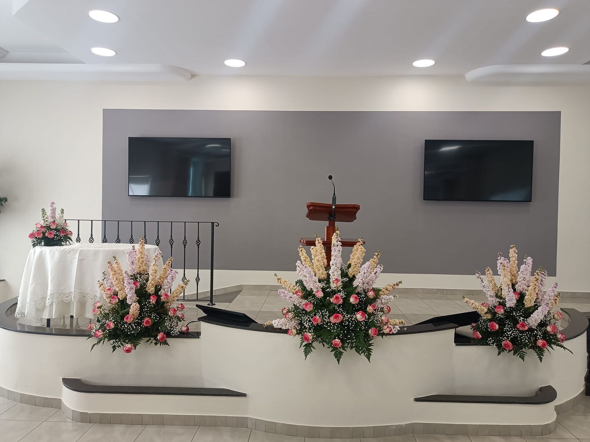 Un podio con dei fiori e un tavolo di fronte in una stanza.