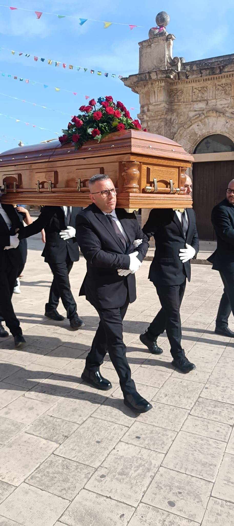 Un gruppo di uomini trasporta una bara davanti a una chiesa.