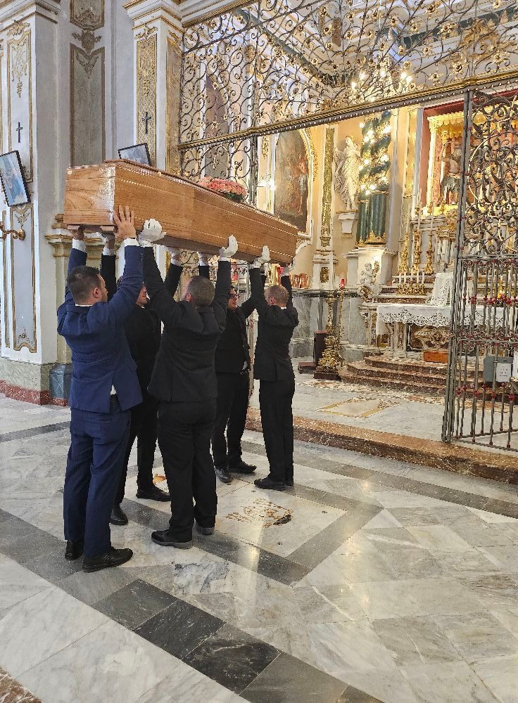 Un gruppo di persone trasporta una bara in una chiesa.