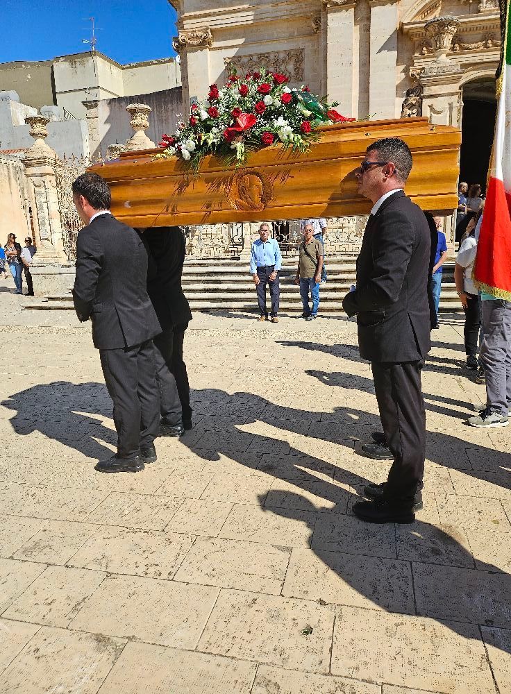 Un uomo trasporta una bara di legno con dei fiori sopra.