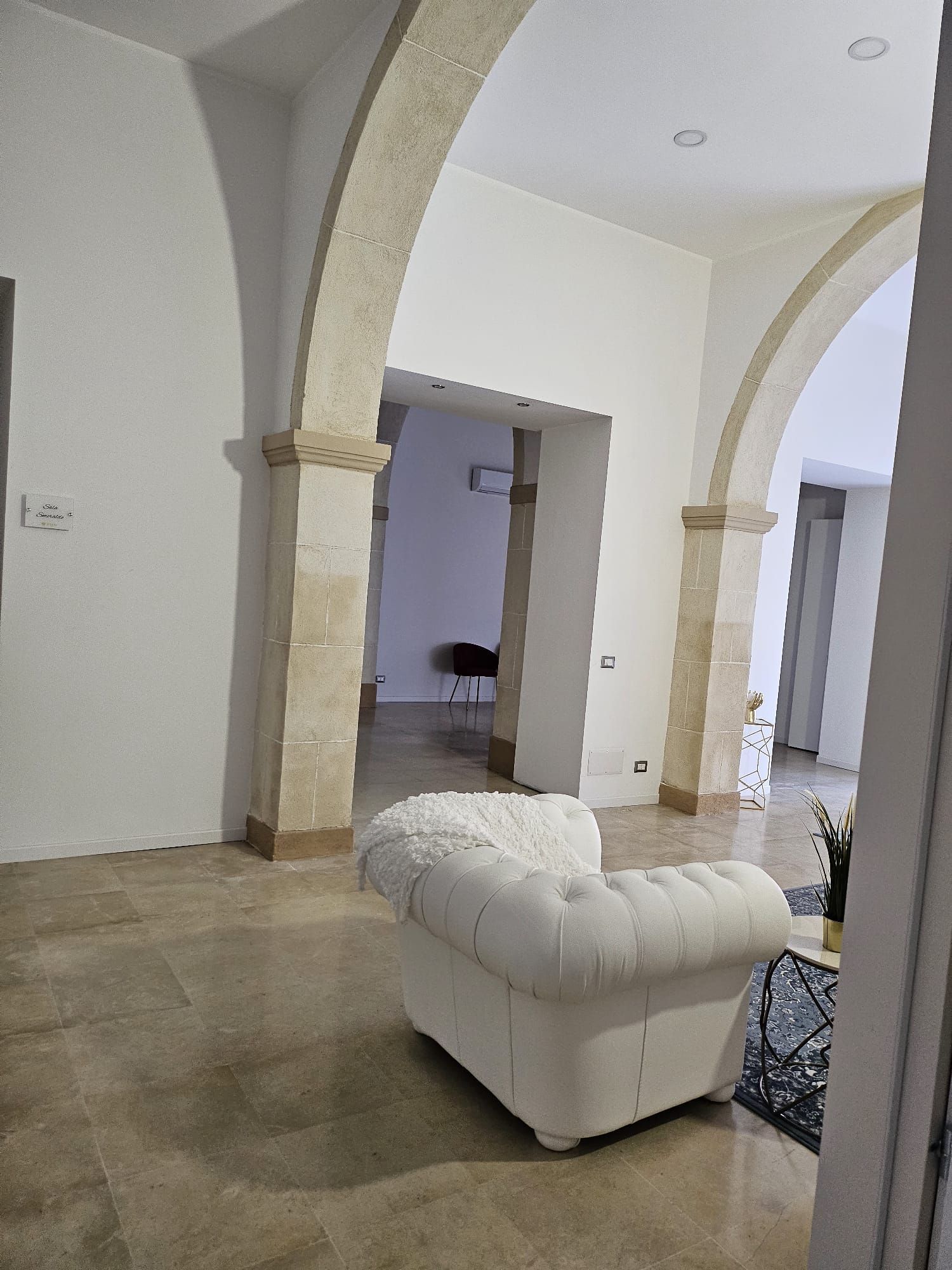Una sedia bianca è posizionata in una stanza con degli archi.