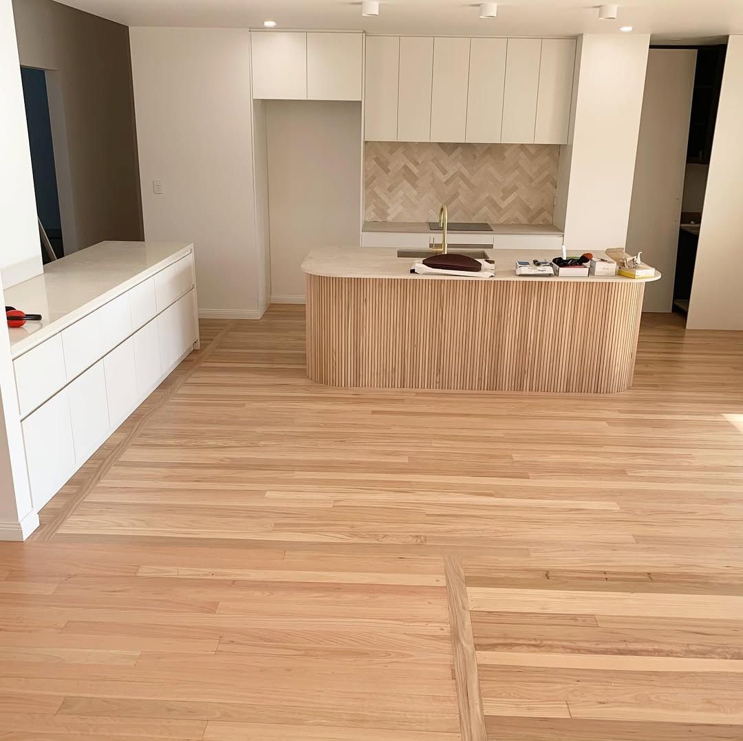 A modern kitchen with light wood flooring, white cabinetry, and a wooden island — CM Timber Flooring in East Ballina, NSW
