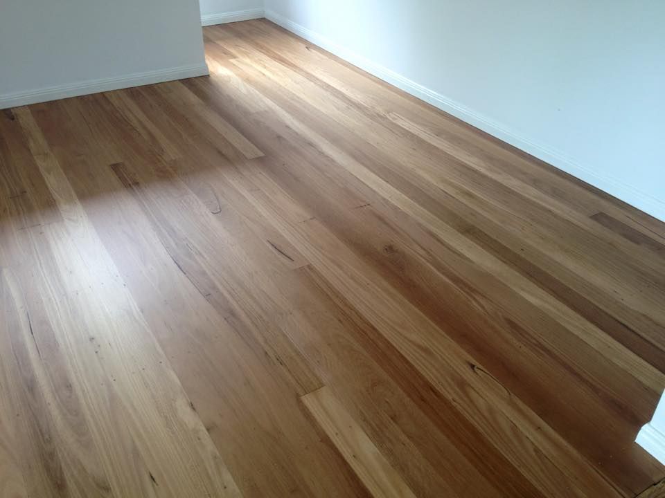 Hardwood floor, light brown colour with natural wood grain, in a room with white walls.