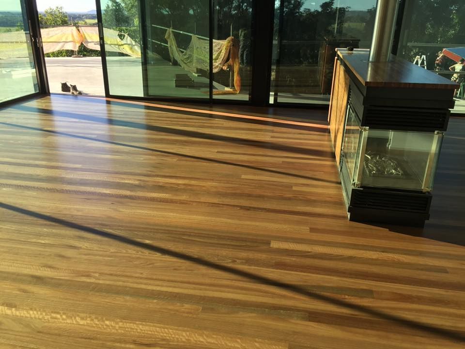 Wooden floor with a dark stove, large windows, and outdoor view — CM Timber Flooring in East Ballina, NSW