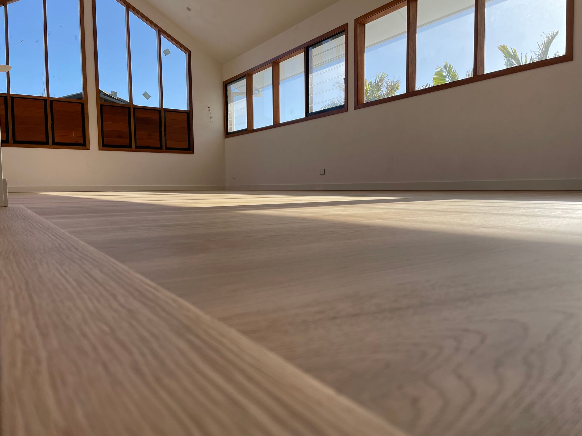 Empty room with light wood floors and large windows — CM Timber Flooring in East Ballina, NSW