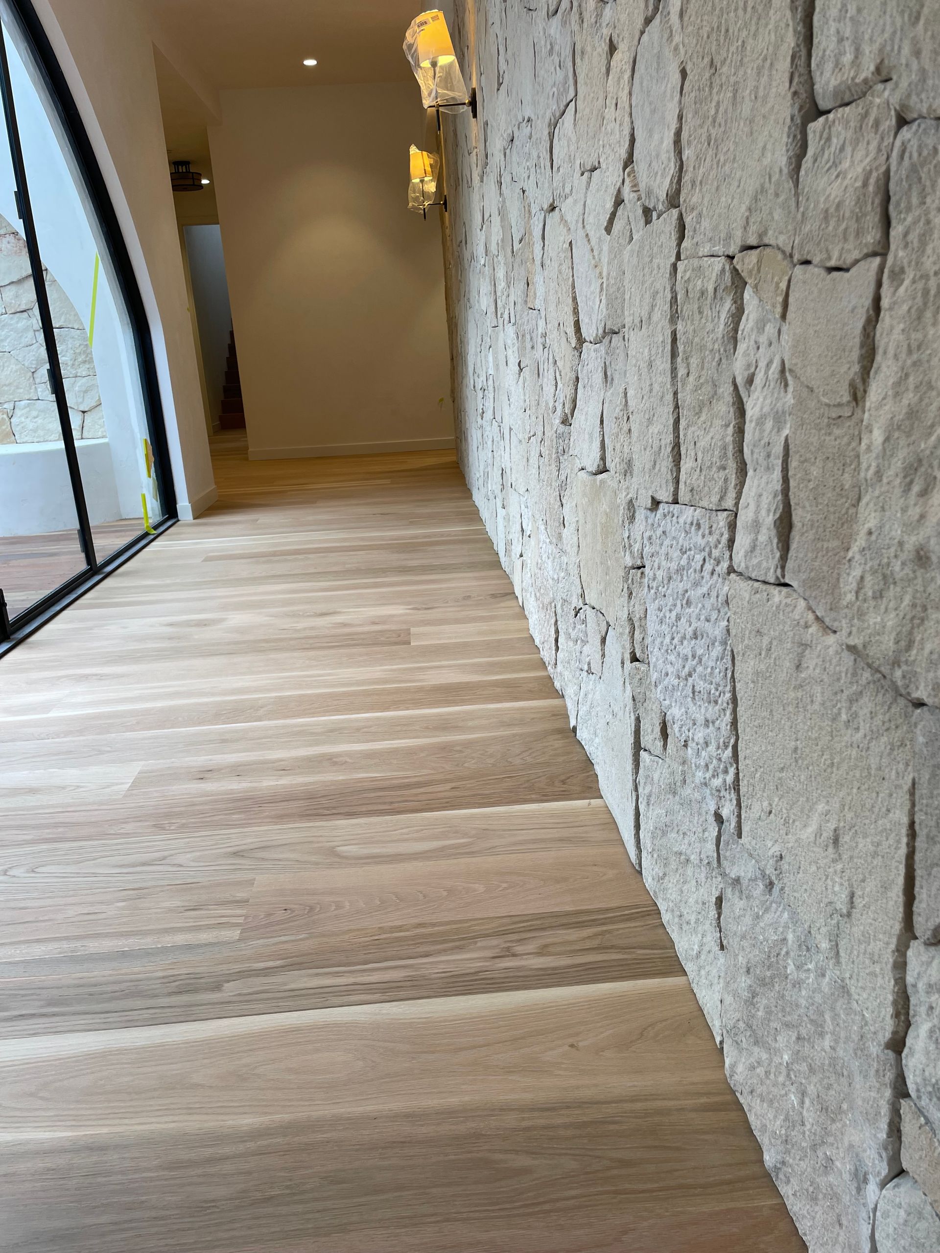 Hallway with stone wall on the right and wooden floor — CM Timber Flooring in East Ballina, NSW