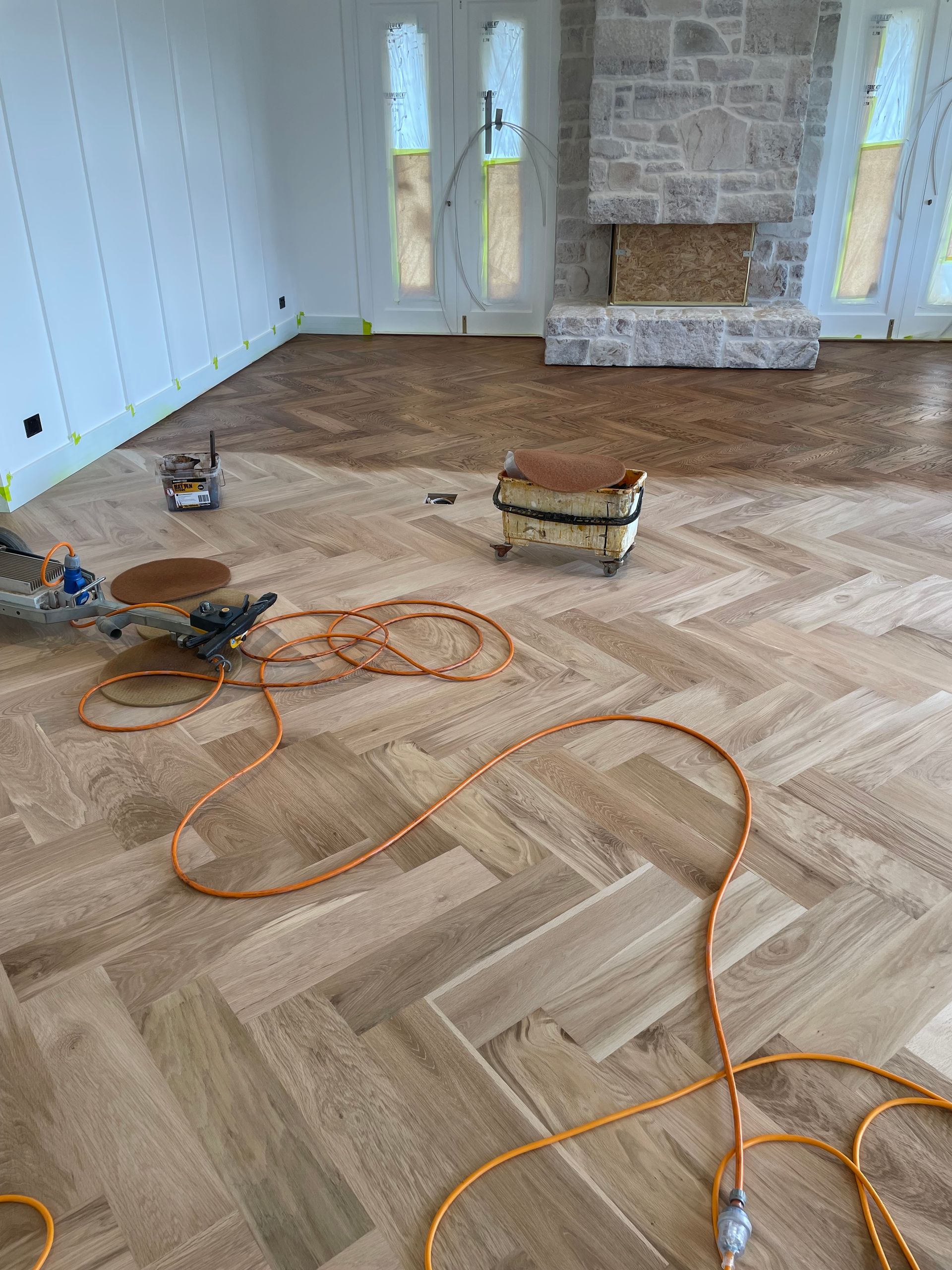 Herringbone hardwood floor installation in a room with a fireplace and windows — CM Timber Flooring in East Ballina, NSW