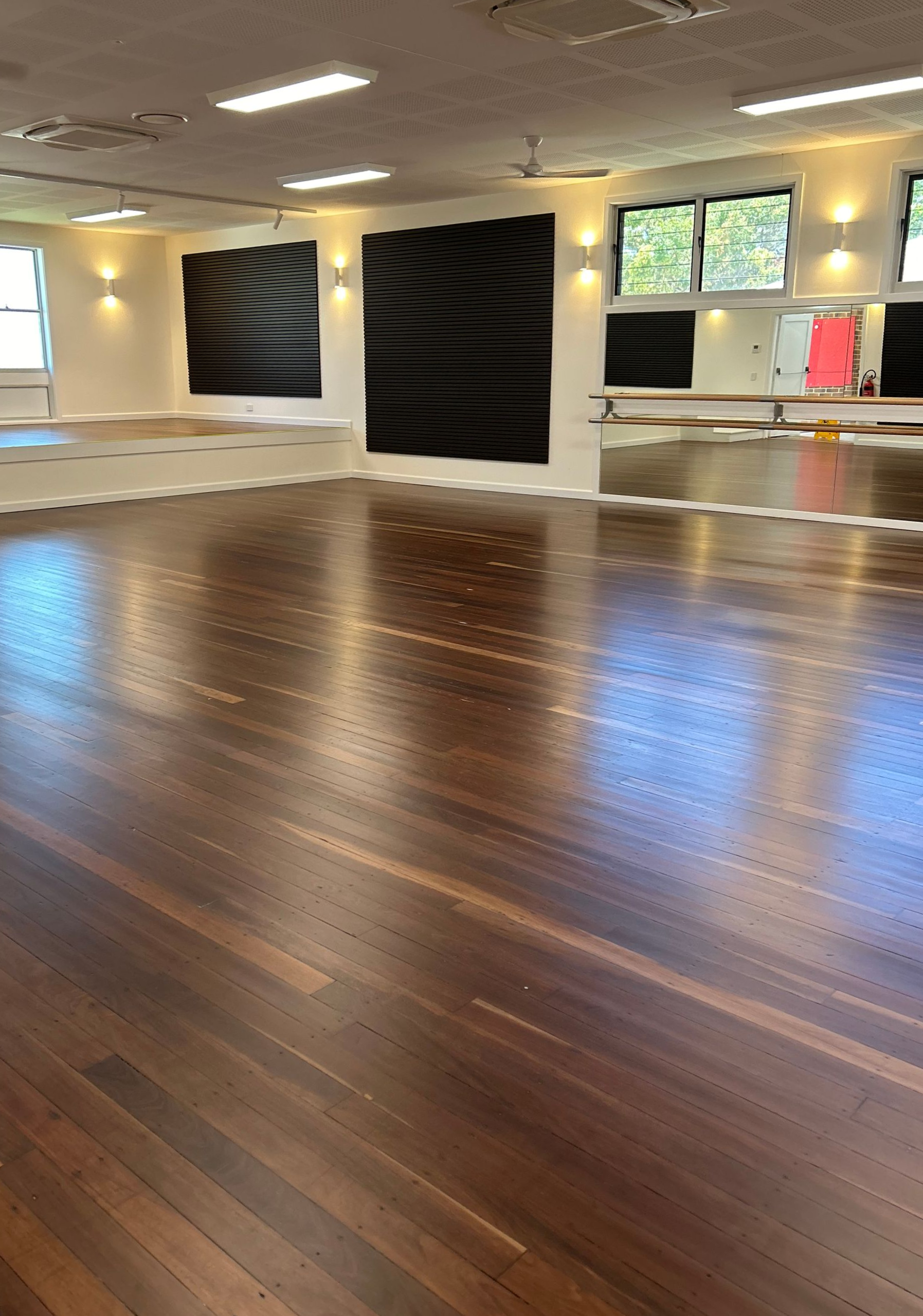 A Hand Brushes Varnish Onto a Wooden Floor With a Yellow-handled Brush — CM Timber Flooring in Tweed Heads, NSW
