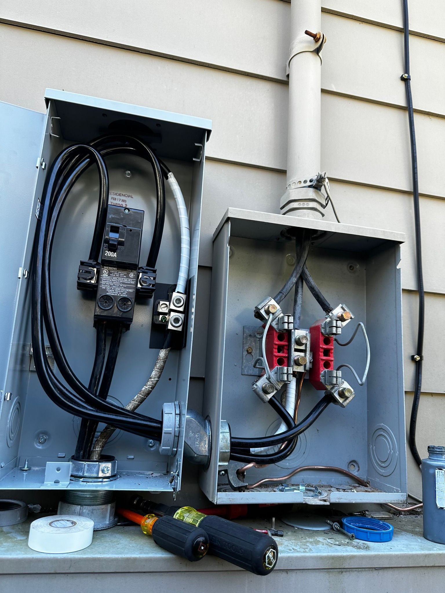 Two electrical boxes are sitting on the side of a building.