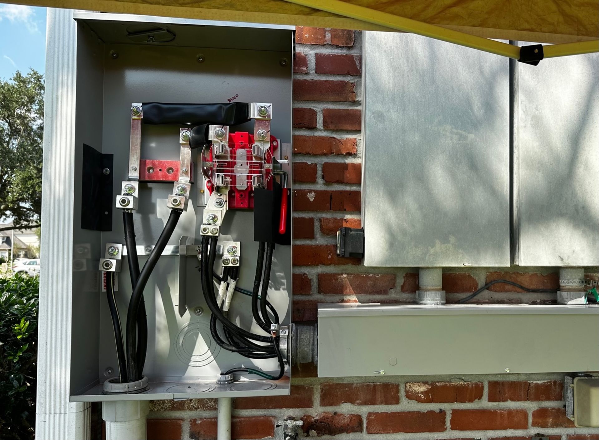 An electrical box is sitting on a brick wall under an umbrella