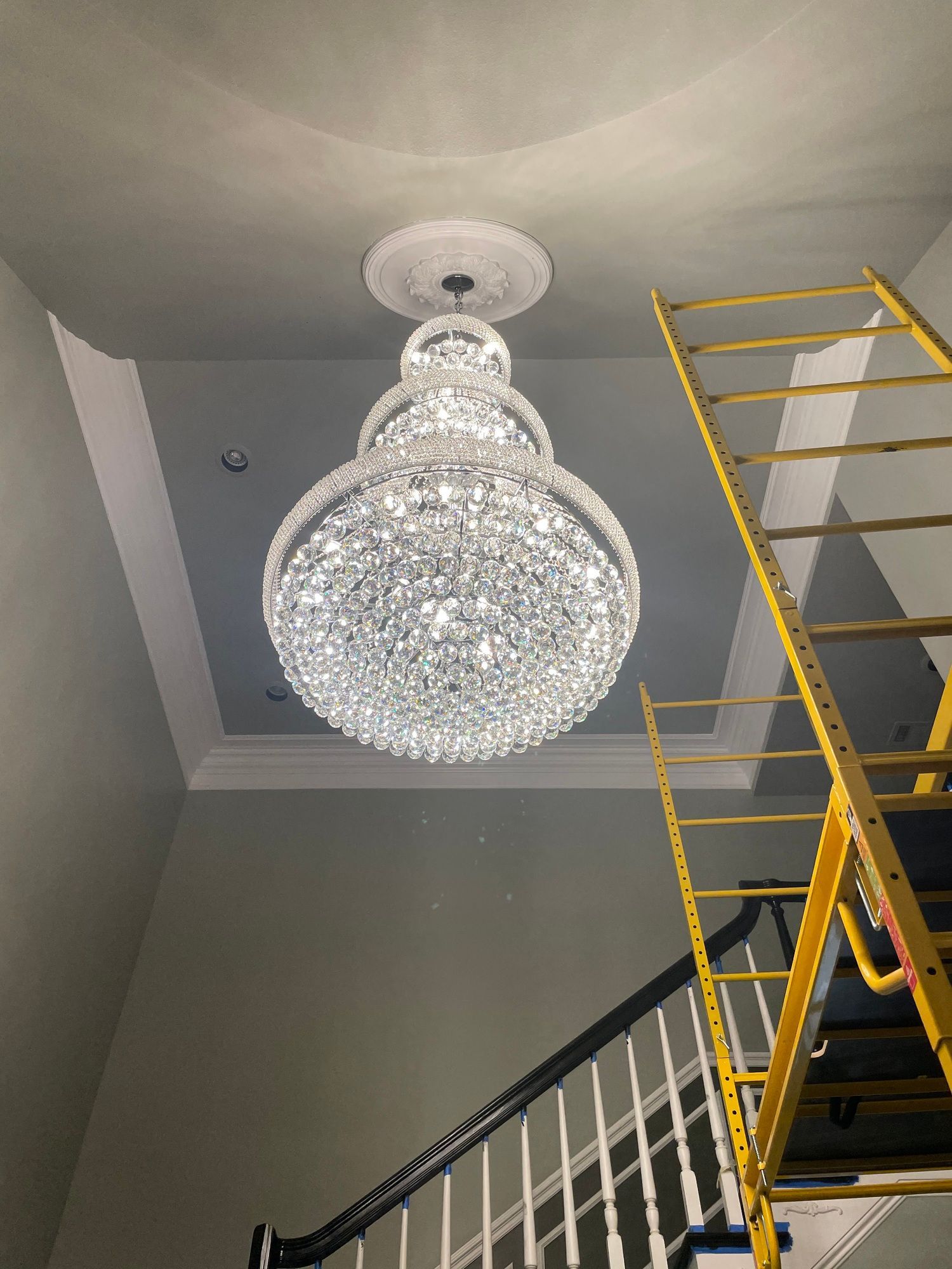 A large chandelier is hanging from the ceiling above a staircase.