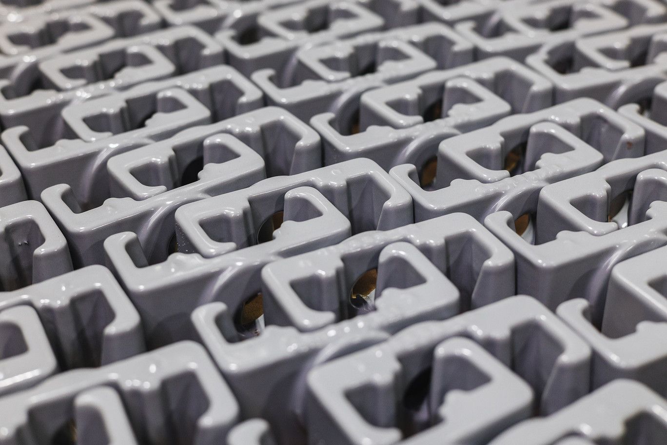 A repetitive pattern of grey, U-shaped industrial plastic components arranged in an organized grid.