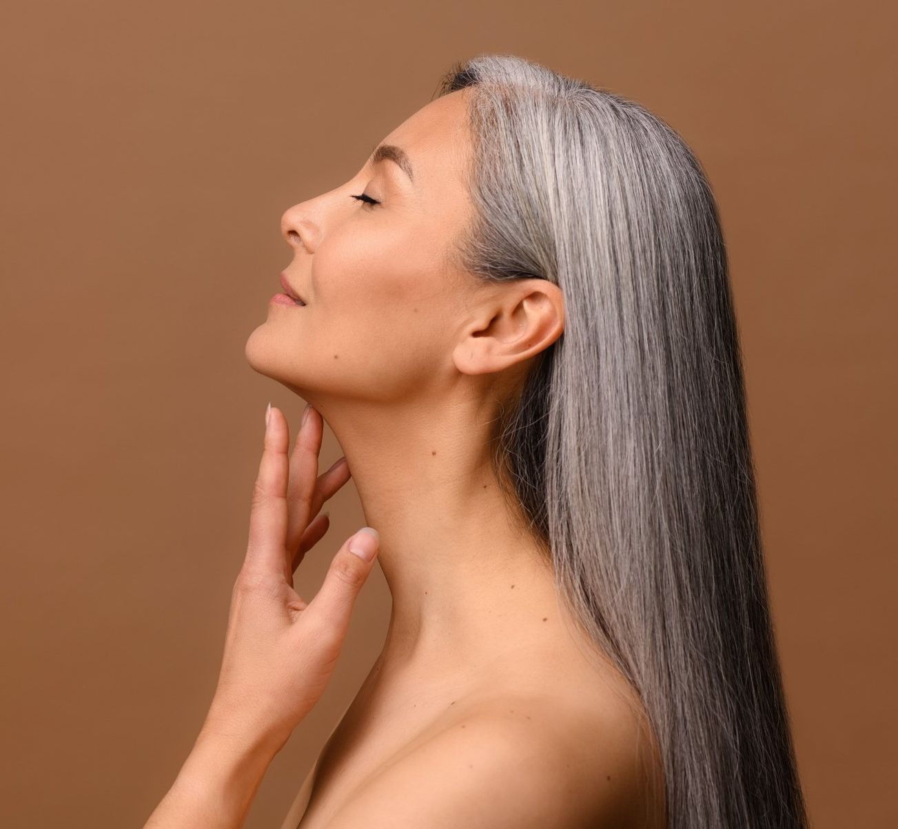 A woman with long hair is holding her hand to her face.