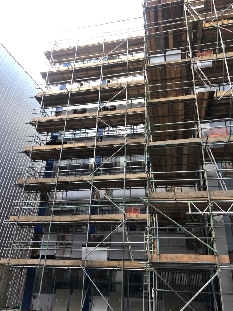 Scaffolding on a multi-story building under construction. Brown wood planks, steel framework.