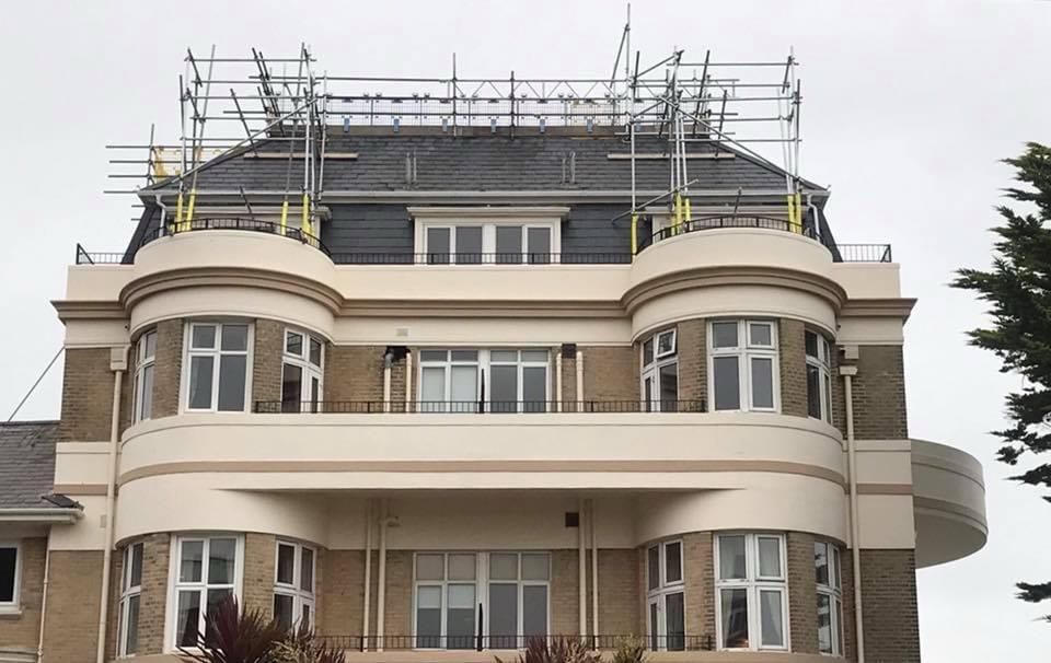 Beige and gray building with scaffolding on the roof.