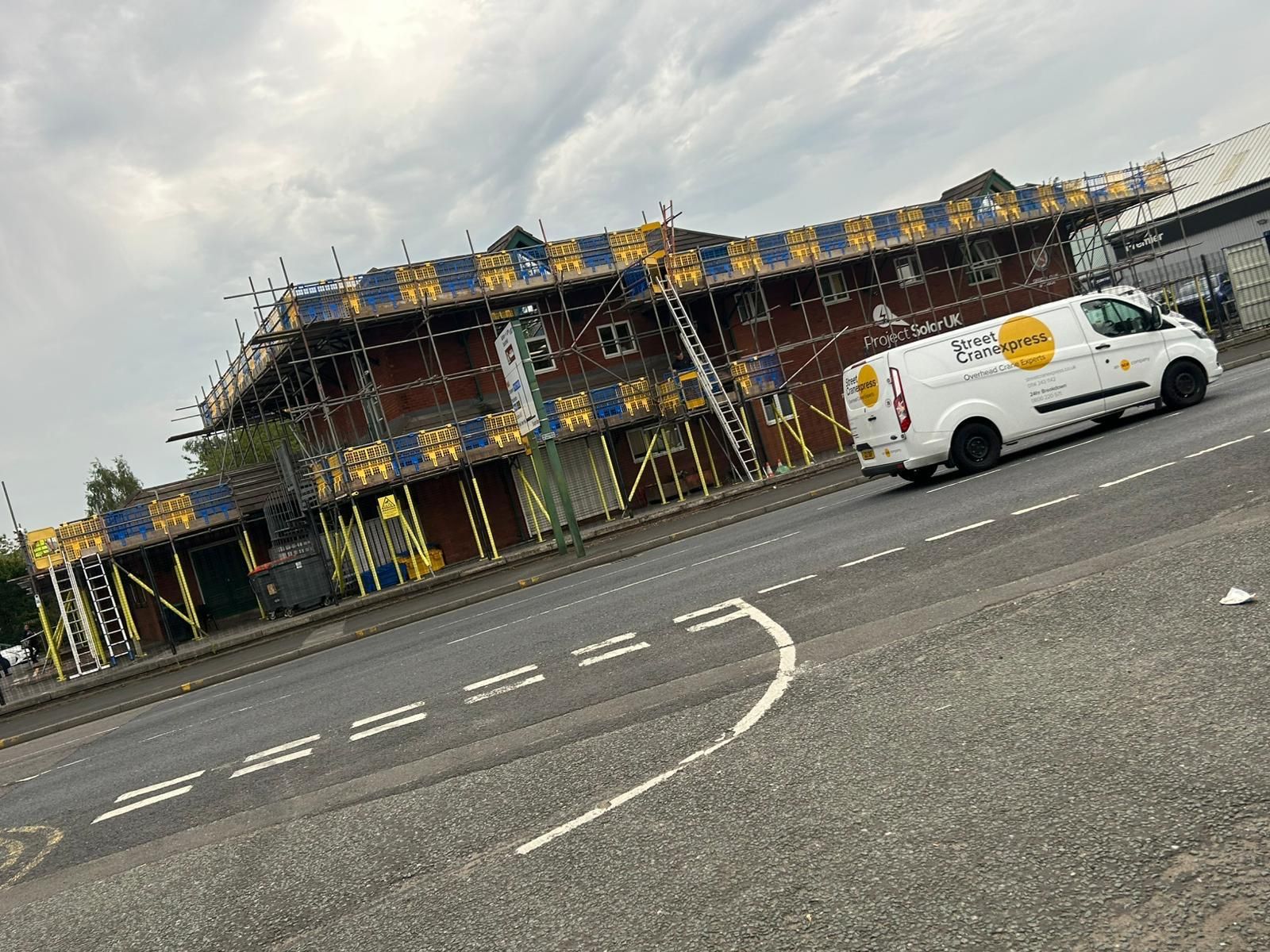 Building under renovation with scaffolding and a white service van.