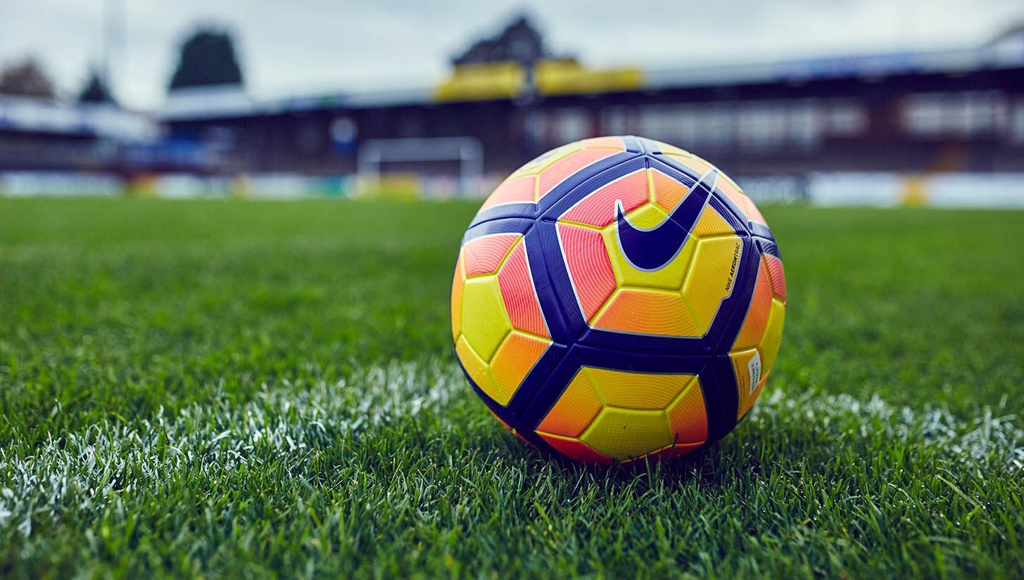 Baseball player sliding into base as another player attempts to catch the ball.