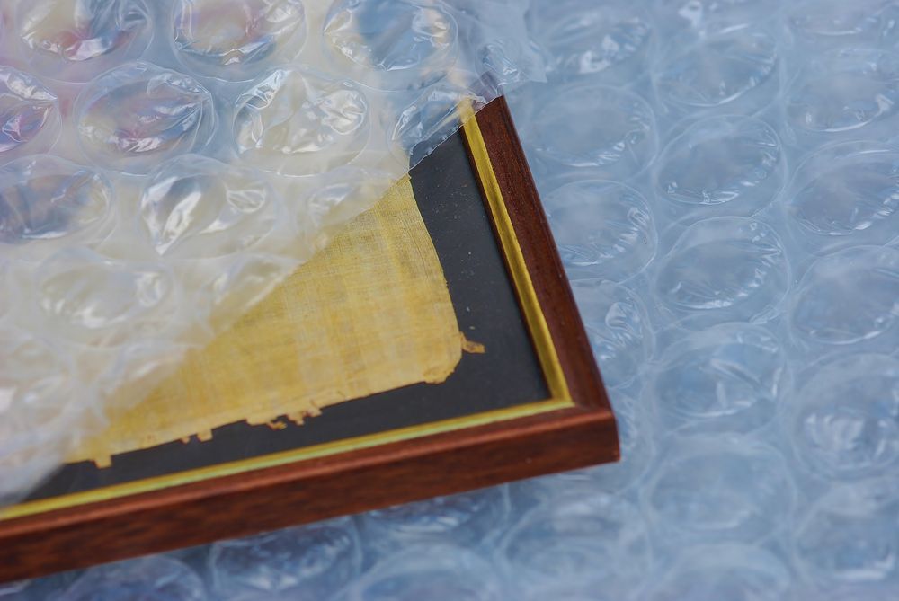 Pink vase on a wood table next to a brown upholstered armchair in a room with a red wall.