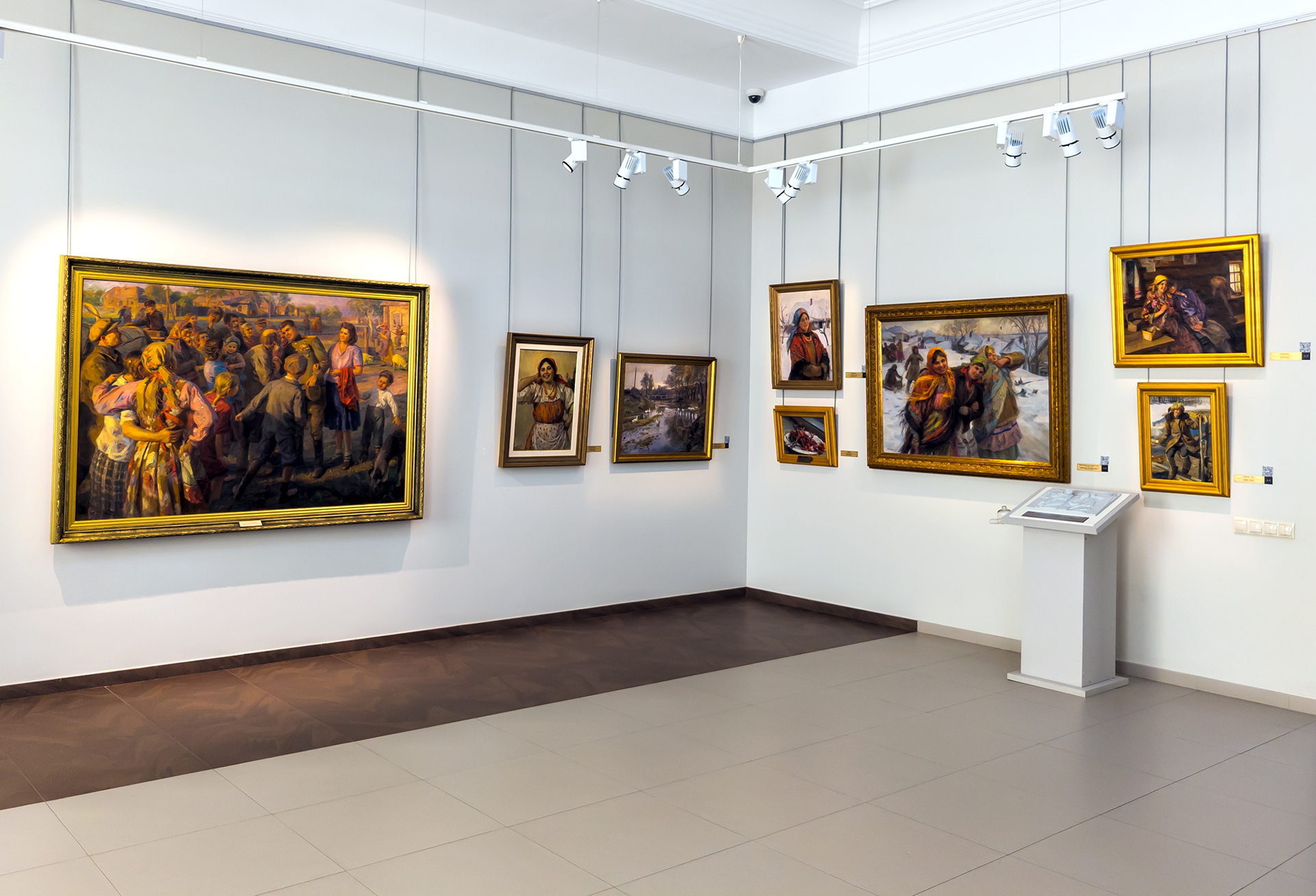 Two movers in blue coveralls pack a cardboard box in a room with brick walls and a window.
