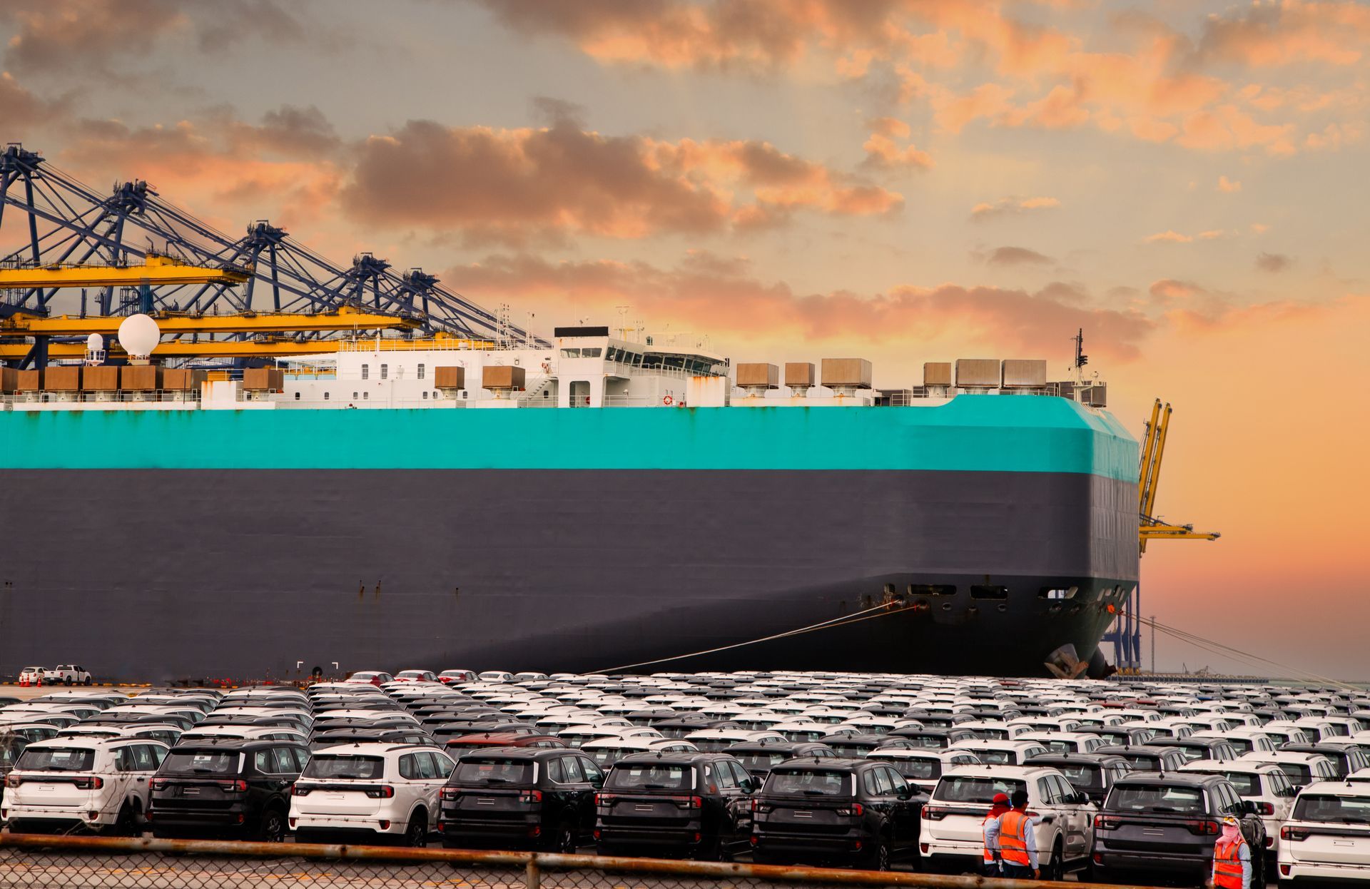 Car carrier truck transporting new vehicles on a highway under a cloudy sky.
