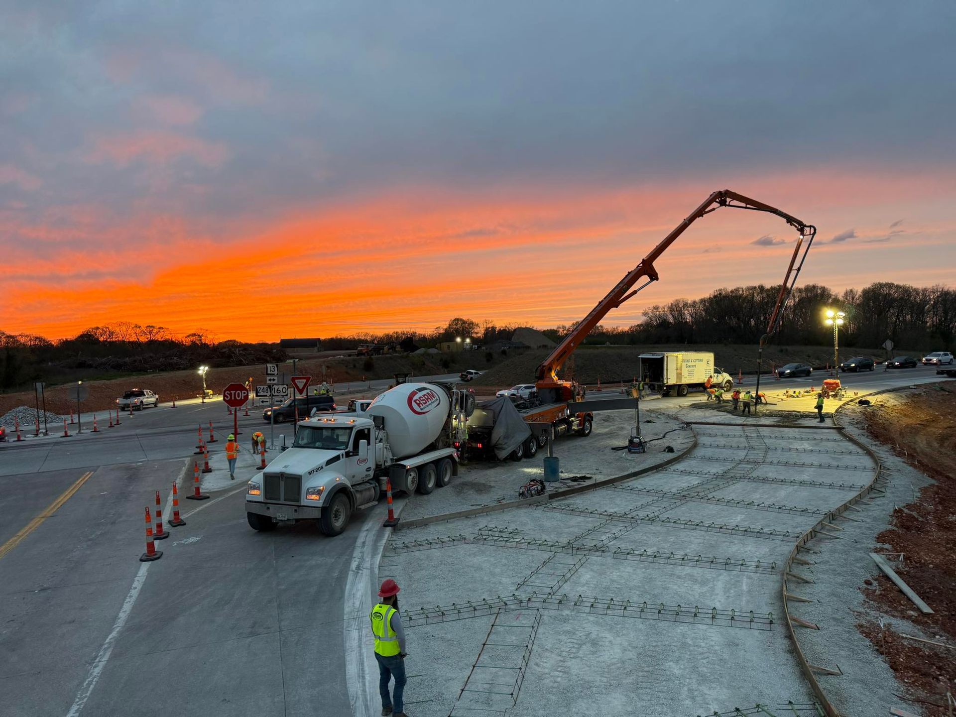 Workers pour concrete for a driveway at sunset.