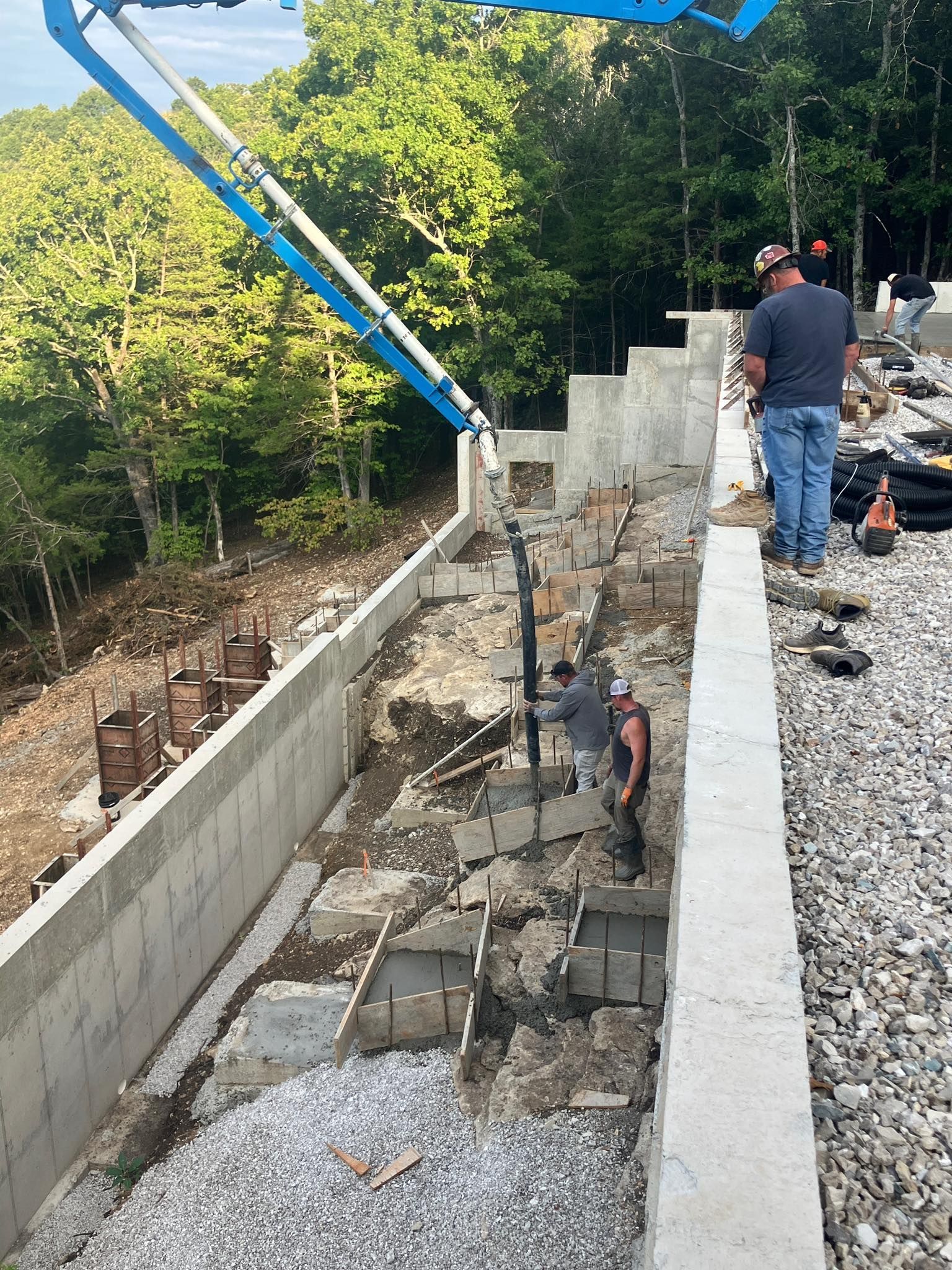 Workers pouring concrete for a residential foundation in the woods