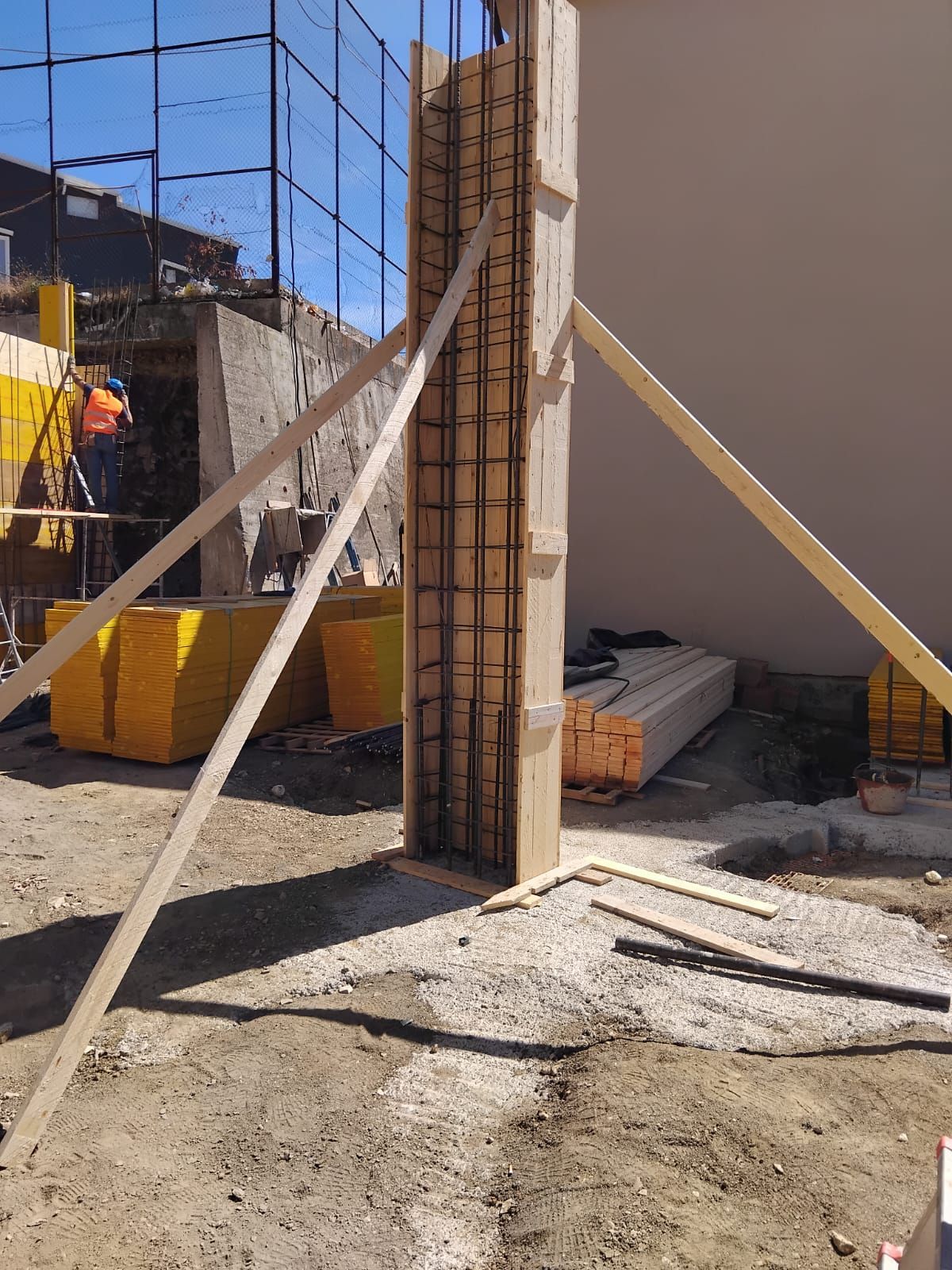 Cassaforma in legno per una colonna di cemento, sostenuta da controventi diagonali, su una superficie di ghiaia in un cantiere edile.