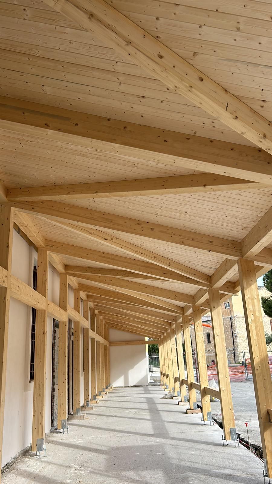 Travi di legno che formano il tetto e la struttura di sostegno di un passaggio coperto.