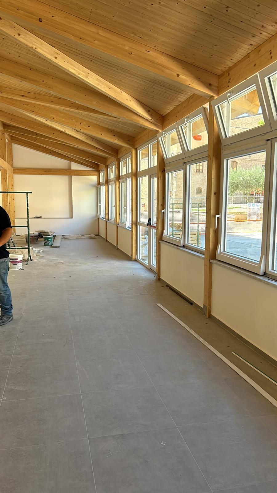 Gabbia di rinforzo in acciaio per una colonna di cemento, su una cassaforma in legno, con un camion blu sullo sfondo.