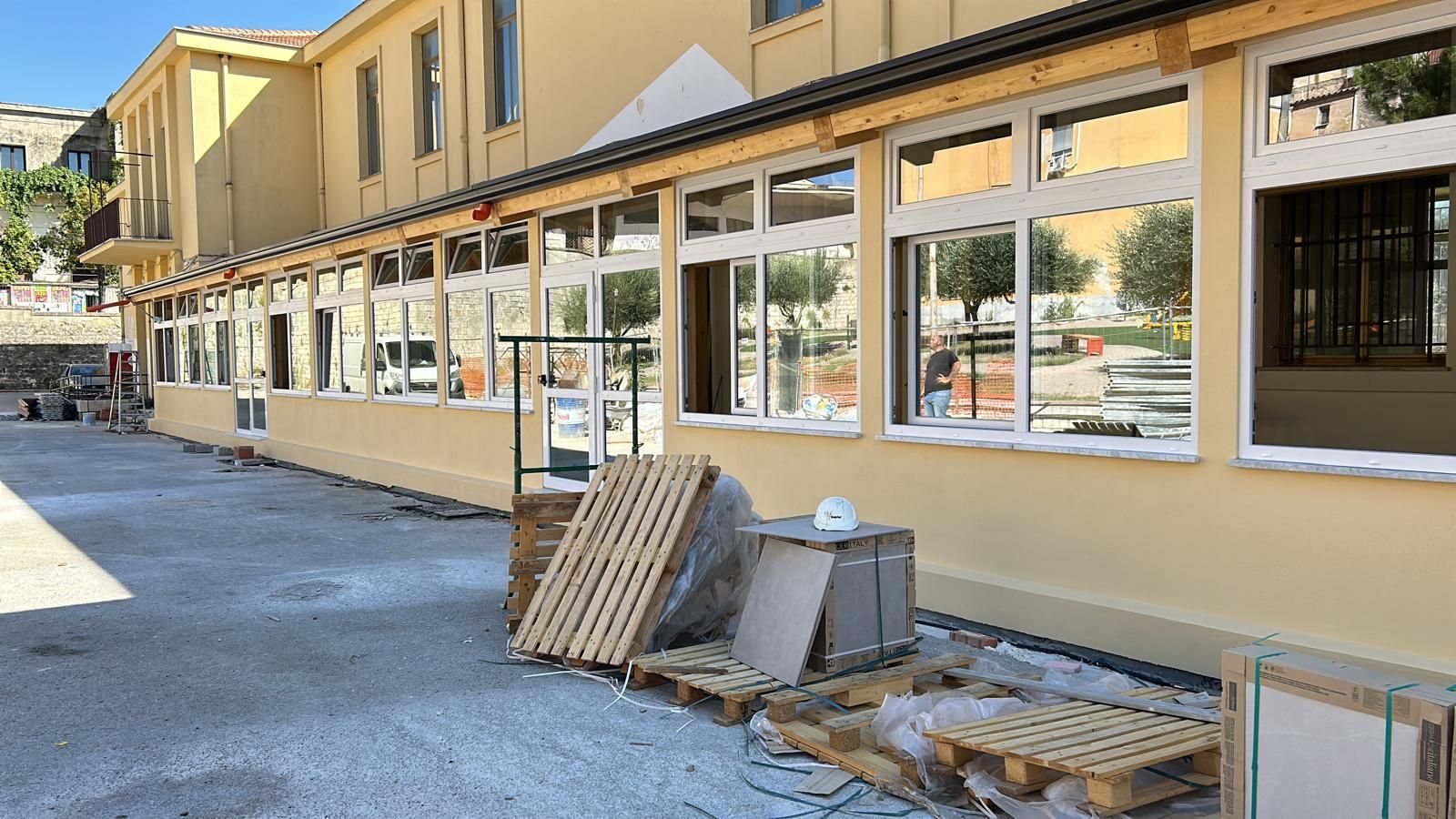 Esterno di un edificio giallo con molte finestre, materiali da costruzione nelle vicinanze.