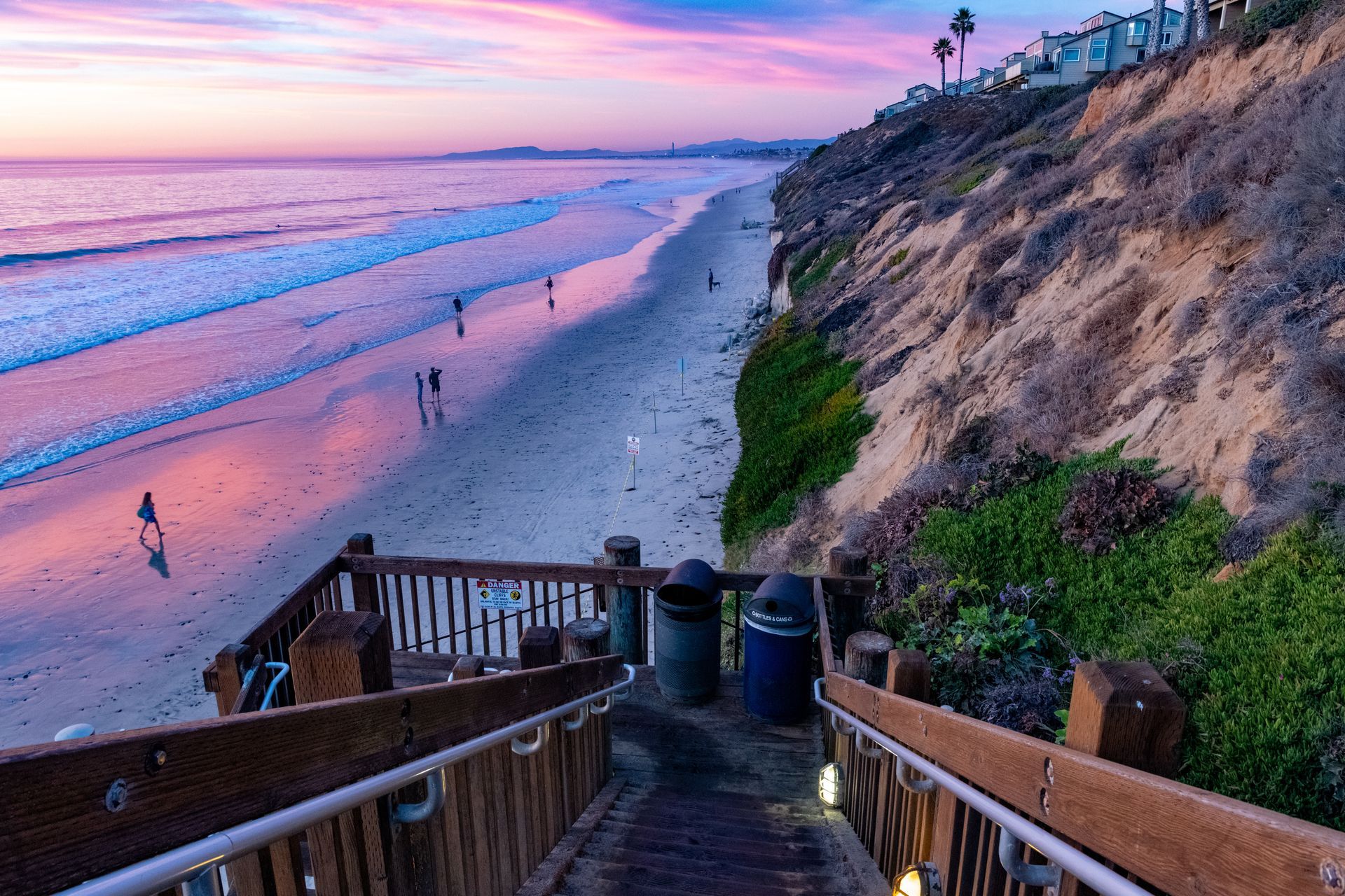 A wooden walkway leading to a beach at sunset.