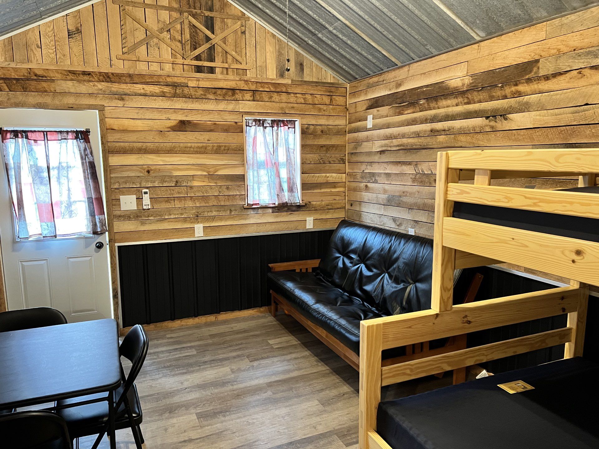 A small kitchenette in a cabin with wood-paneled walls, a white sink vanity, a mini-fridge, and a microwave on a shelf.