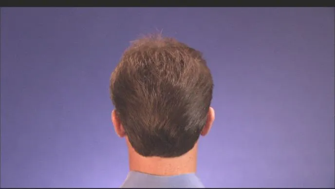 Back of a person's head with short, dark hair against a purple background.