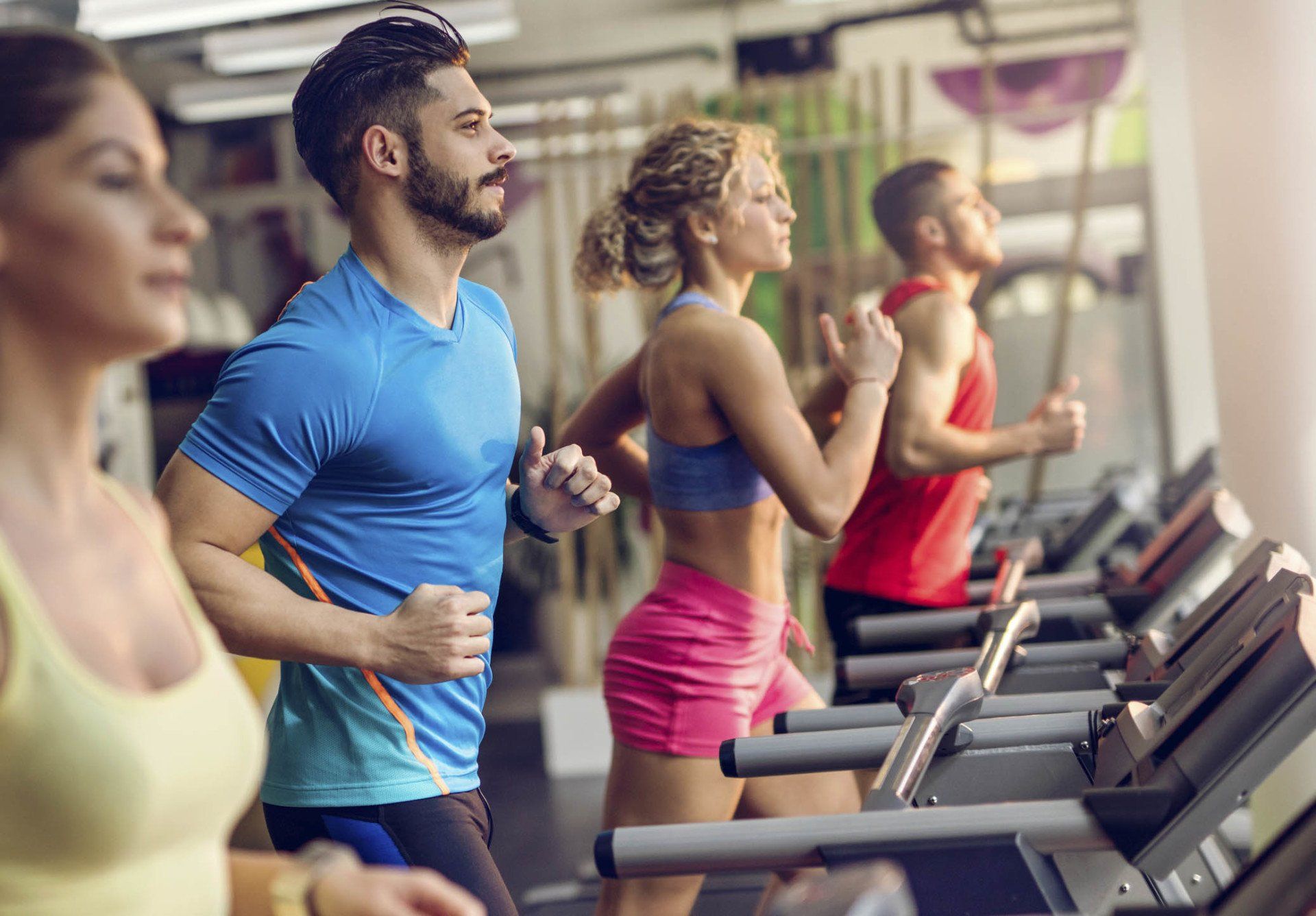 Group of young people running on treadmills in a gym.