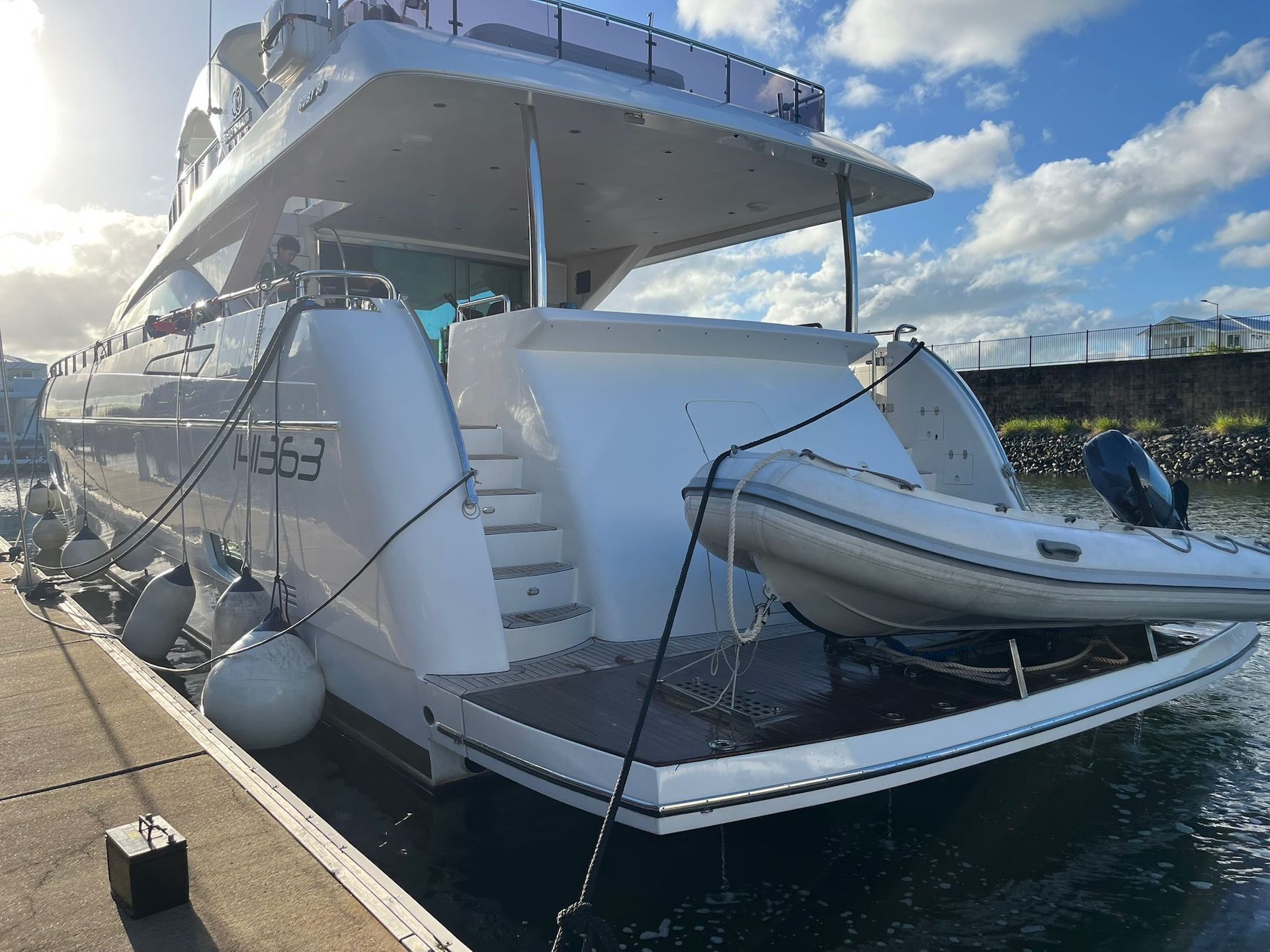 Person Holding a Black Boat Propeller Near a Motor on a Boat