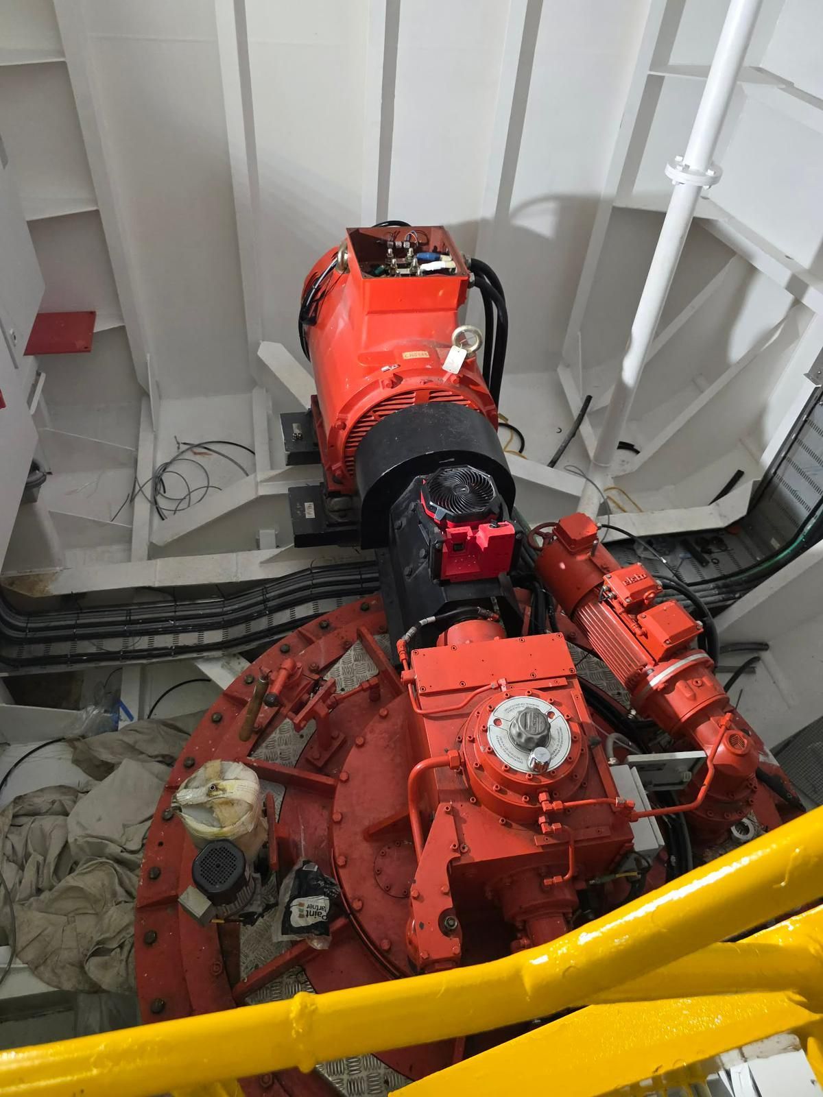 A high-angle view of a bright orange industrial mechanical crane slewing gear assembly mounted on a white painted deck — Ocean Mate Marine Services in Coomera, QLD
