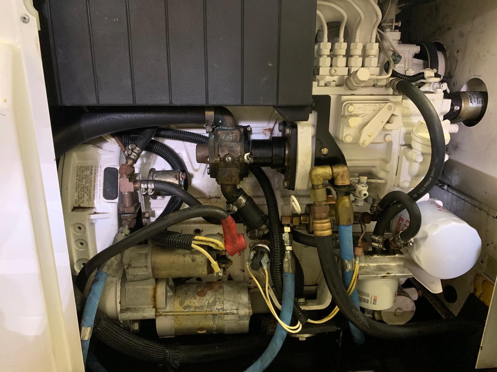 A white marine diesel engine in an engine compartment featuring various hoses, electrical wiring, and a fuel filter — Ocean Mate Marine Services in Coomera, QLD